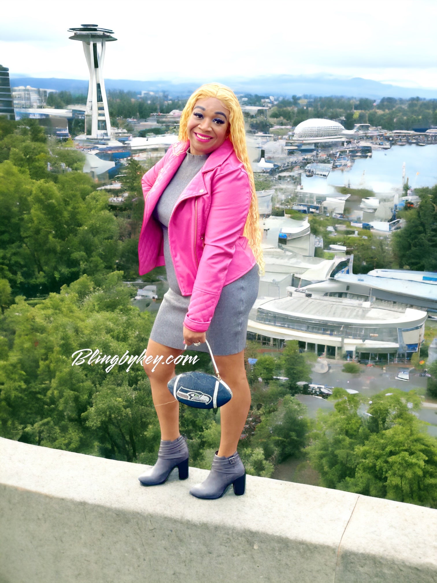 Person in pink jacket and gray outfit with Seattle skyline and Space Needle in the background