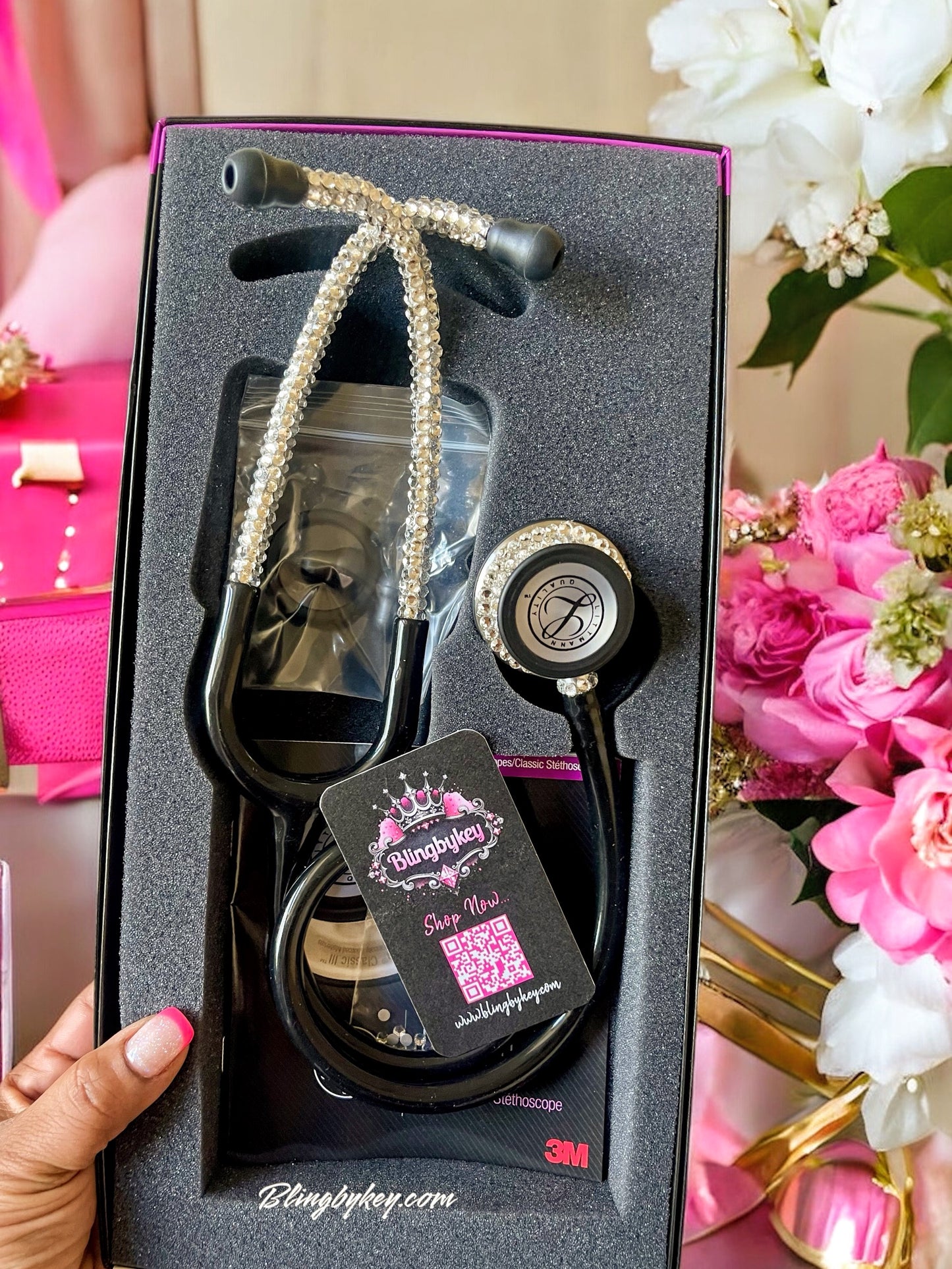 Custom Black Littmann Classic III Stethoscope with handplaced Clear Rhinestones by Blingbykey in its box with decorative flowers in the background