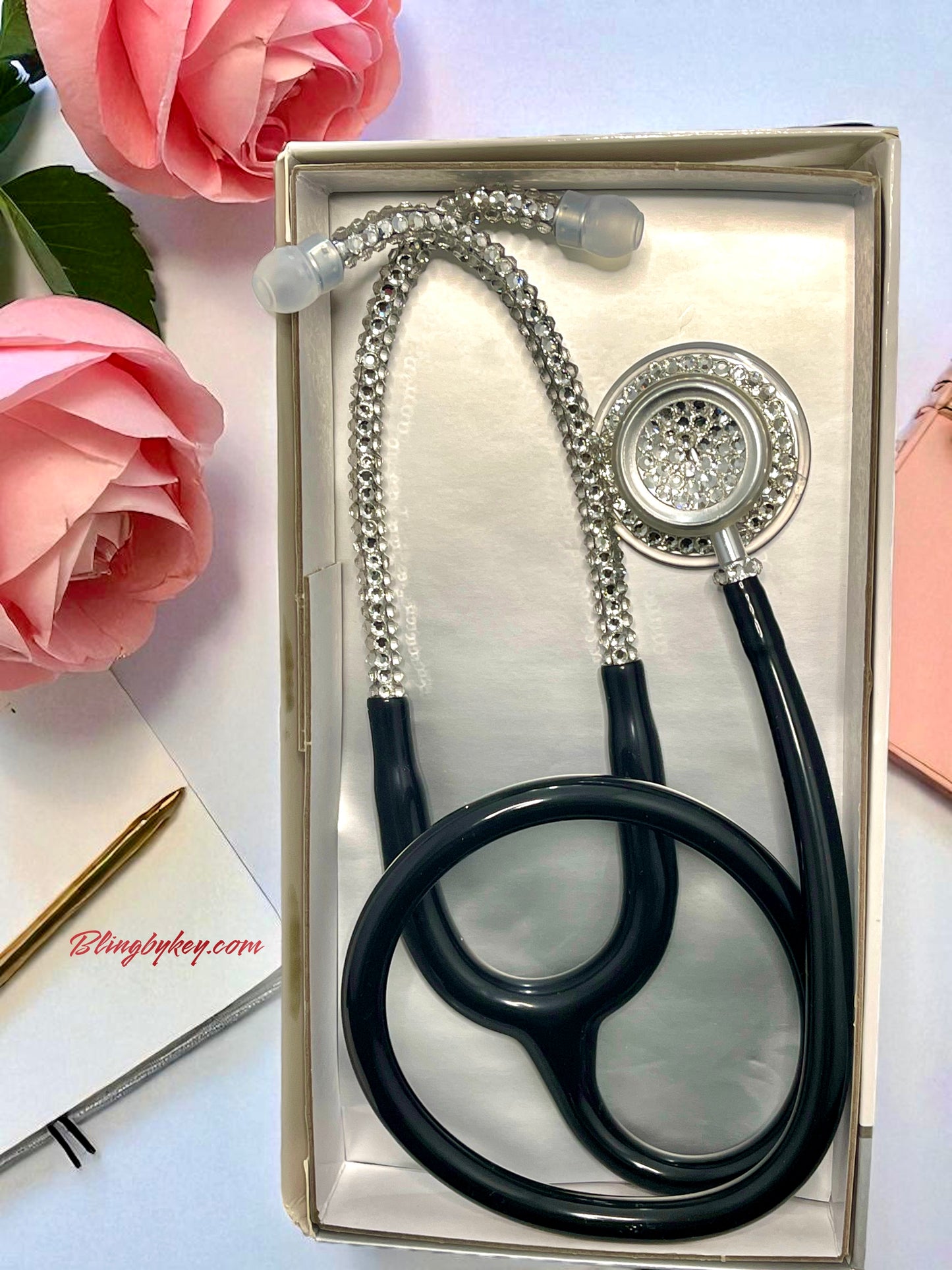 MDF Acoustica Black stethoscope, clear rhinestones  in a box with pink flowers and a pen on a white background